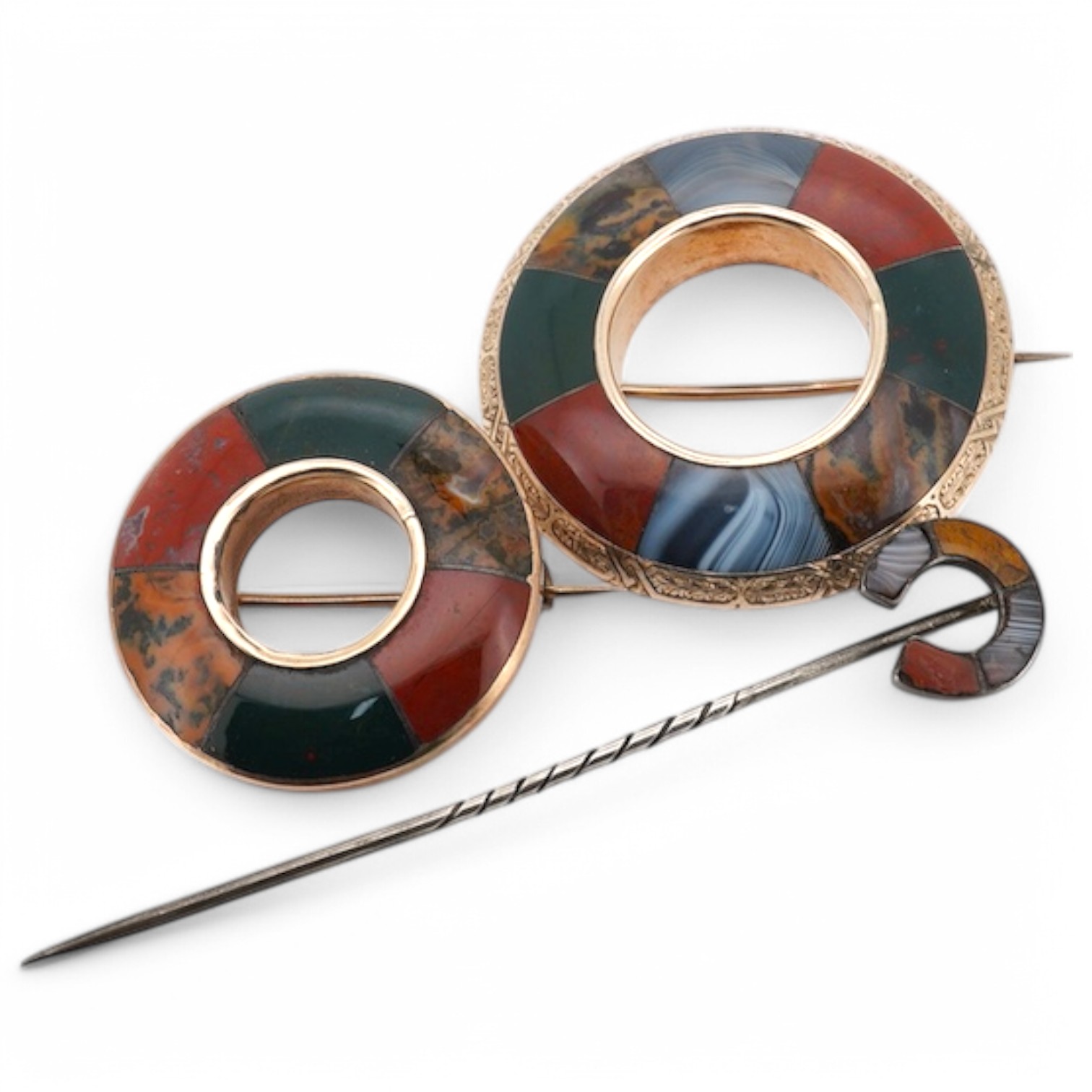 Two Scottish hardstone brooches and a stick pin, late 19th century, the brooches of annular design, the stick pin of horseshoe design, each inlaid with panels of jasper and bloodstone, largest brooch 4cm diameter, combin